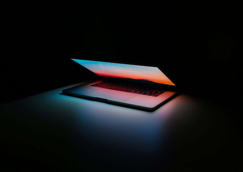 Laptop half closed in the dark, glowing.